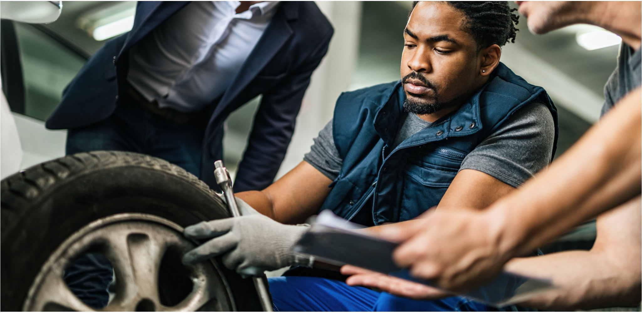 auto mechanics repairing tire of customer s car at repair workshop 1 1 2048x999 1 الجهود الحديثة في الحد من الضوضاء الصادرة من الإطارات